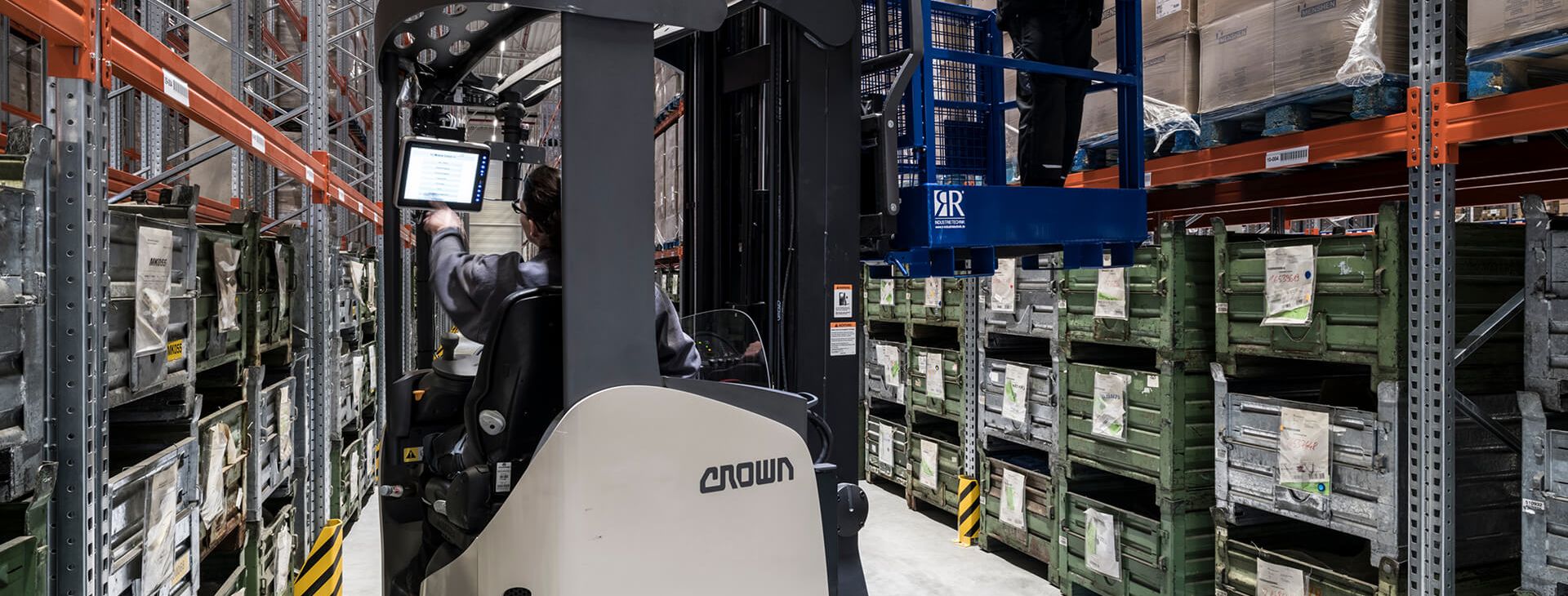 Smart IT solutions for logistics put companies in a competitive position. An employee stands on a mobile lifting platform in a warehouse and uses mobile devices.