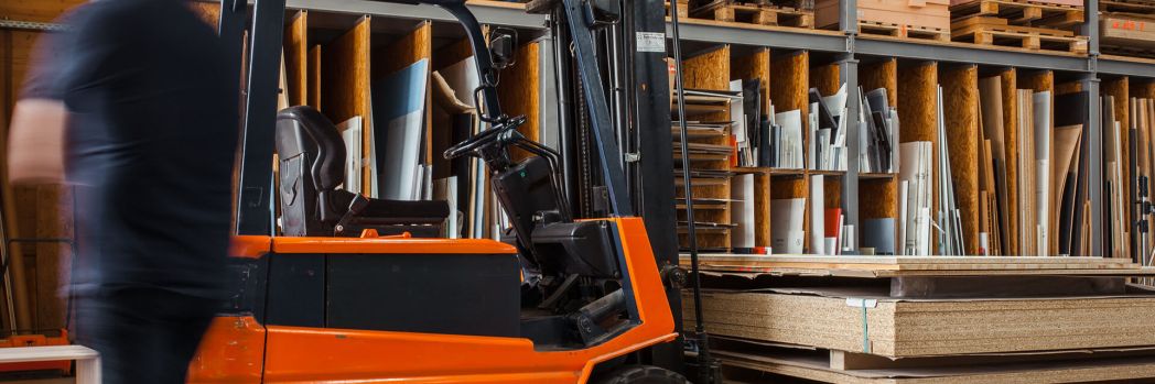 General cargo forwarding in networks requires organized cooperation with many partners Man walks by next to a red forklift in the warehouse.
