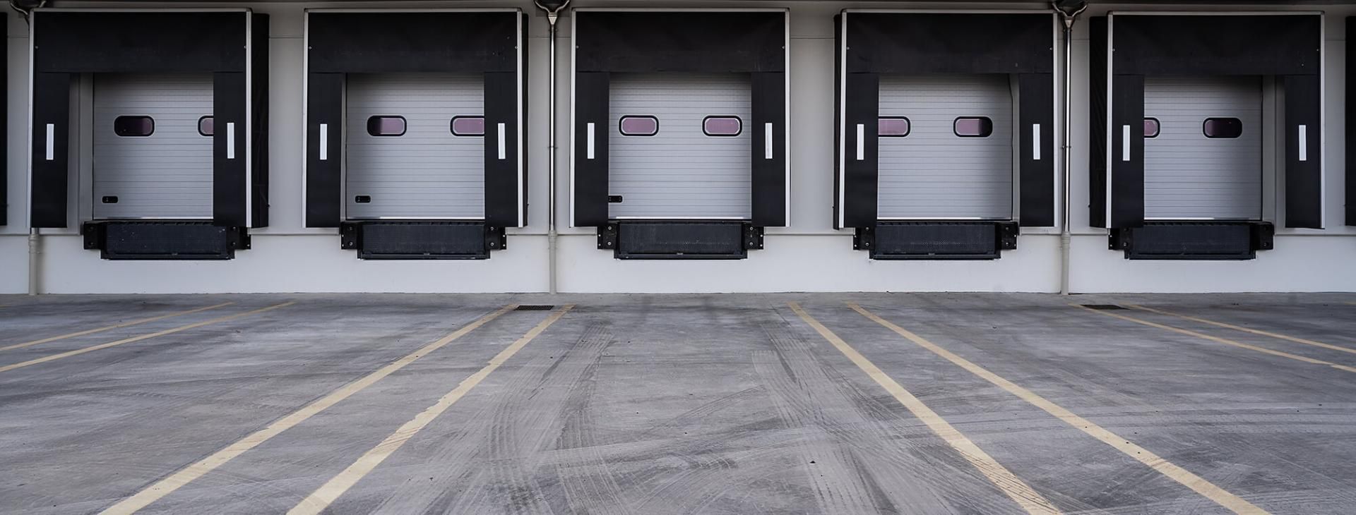 The EIKONA Logistics Cloud controls shipping processes of shippers. Five white loading ramps of a warehouse.