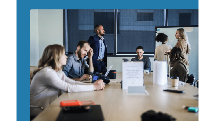 IT security consulting for the protection of data and IT systems in logistics. Seven people stand and sit in a meeting room and discuss IT security issues.