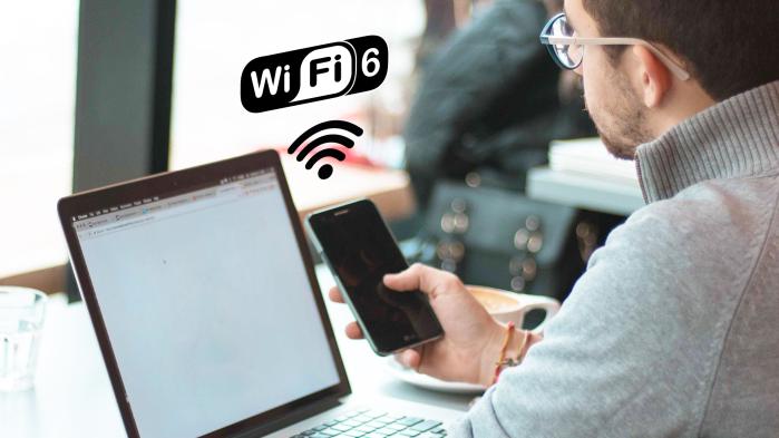 Auf dem Bild sind ein Laptop, ein Smartphone und der Schriftzug "Wifi 6" sichtbar.