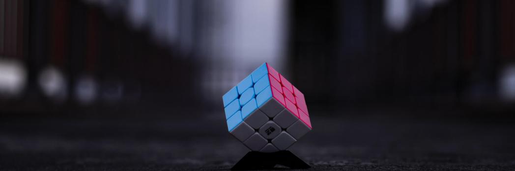 Rubik's cube with blue, pink and white side lies on a dark road
