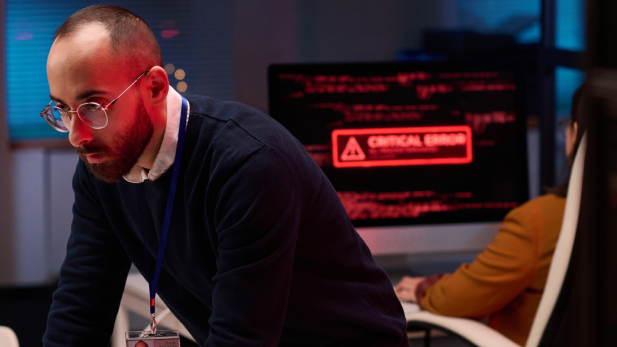 A man looks concentrated at a screen during an IT emergency.