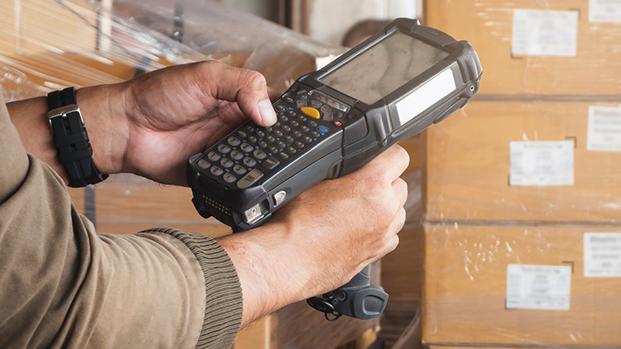 Logistiker scannt Pakete mit seinem Handheld welcher dank MDE effizient verwaltet wird