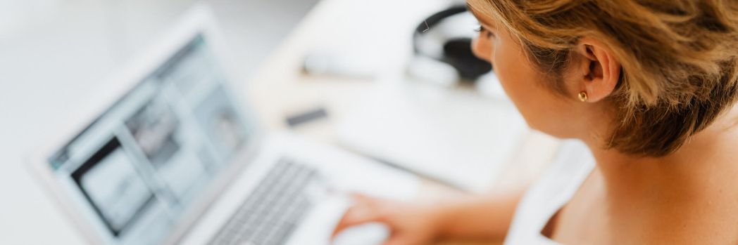 Logisticians create the best service and maximum transparency for customers with digital solutions. Blonde Frau sitzt an einem Schreibtisch und tippt auf einem Laptop
