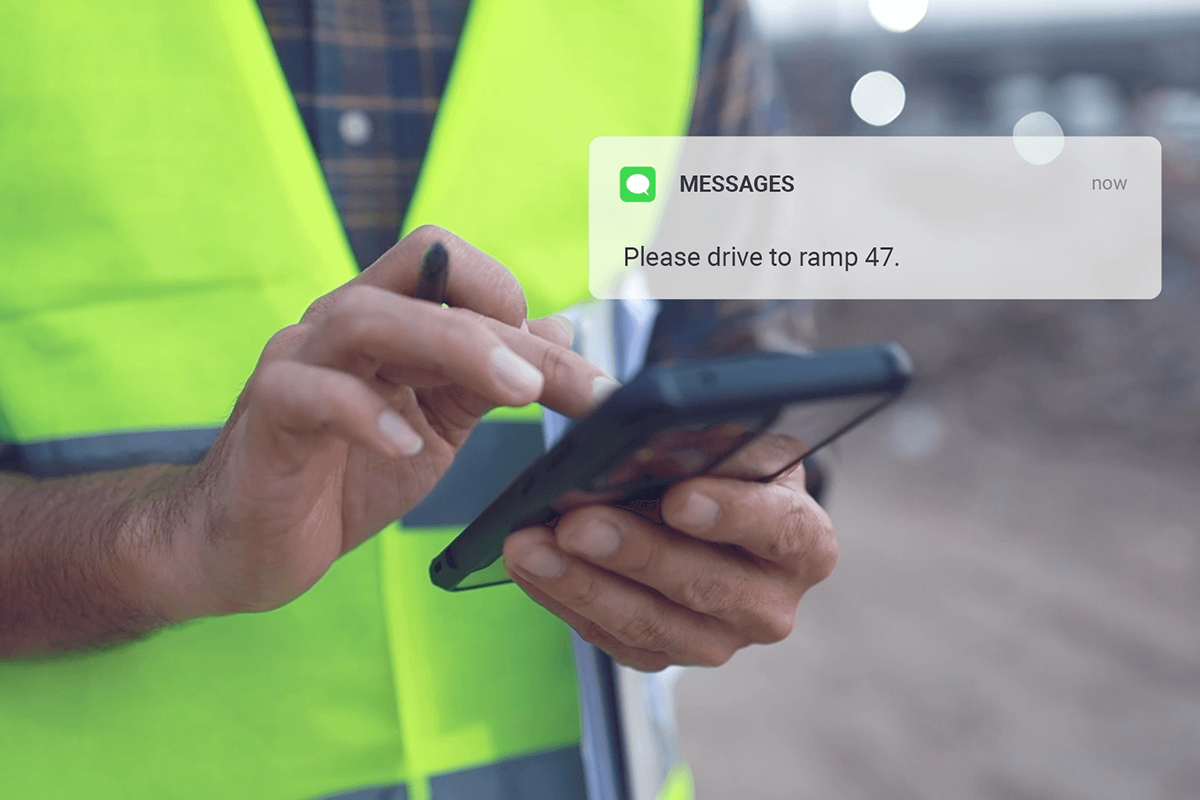 While a man's hand taps on a smartphone, the message is displayed: Please drive to ramp 47.