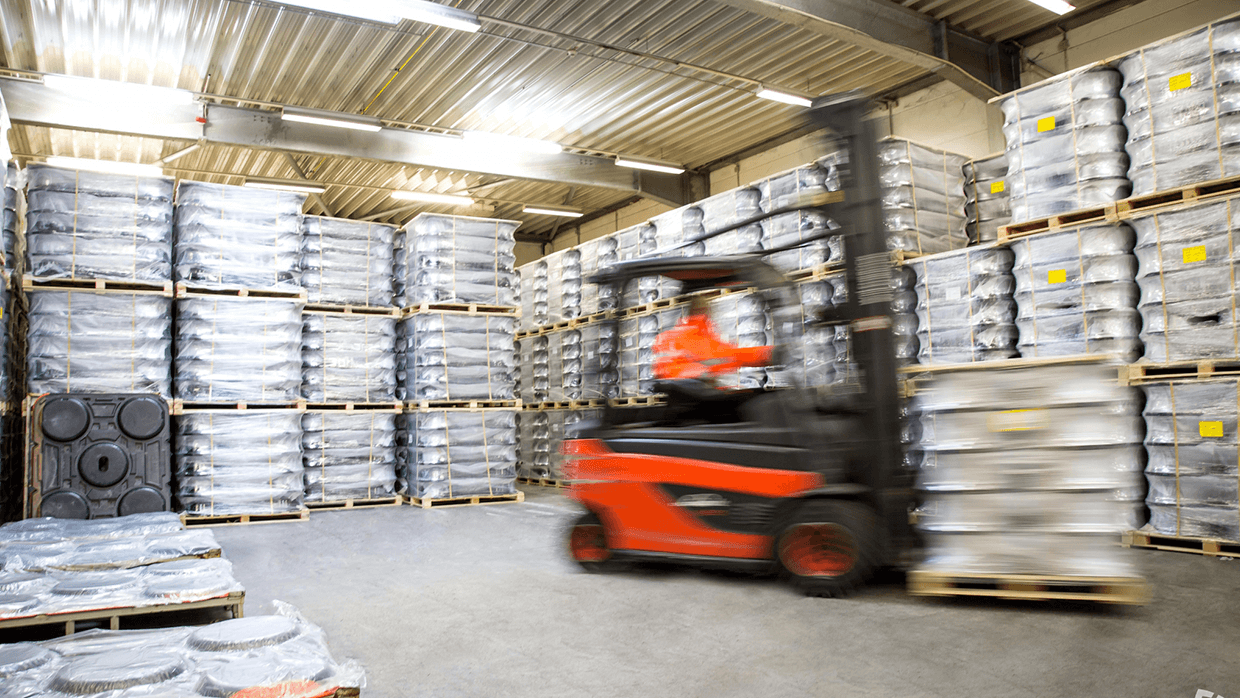 Red forklift truck moves pallets through a warehouse.
